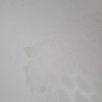 Bathtub Resurfacing - Before - A light-colored surface, possibly a wall or ceiling, showing water stains and discoloration. - Refinishing Services Near Me