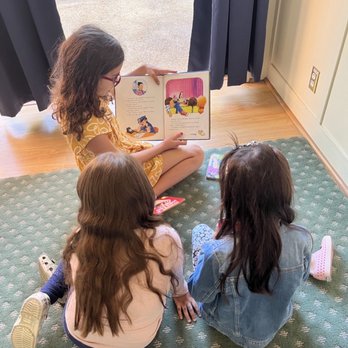 Ventana School - Buddy program, 3rd grader reading a book to her buddies in 1st graders - Preschools Near Me - Los Altos, California