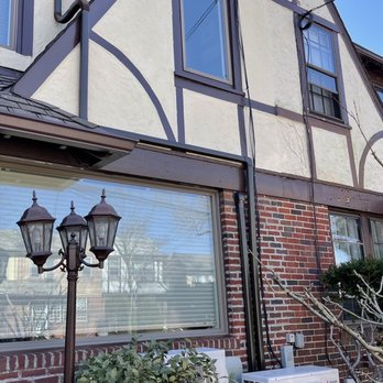 LINLI HVAC - Exterior ductwork and condenser install - A house exterior with brick and stucco siding, decorative trim, and two windows. An outdoor lamp post and air conditioning unit are also visible. - Heating & Air Conditioning/HVAC Near Me - Flushing, New York