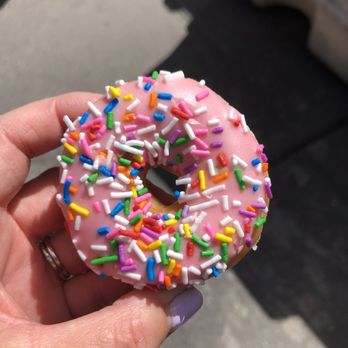 Krispy Kreme - a person holding a donut with sprinkles - Donuts Near Me - New York, New York