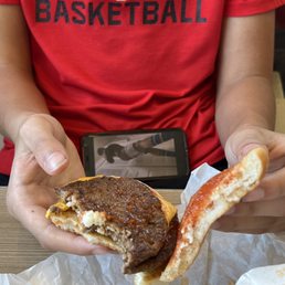 a man holding a hamburger and bacon