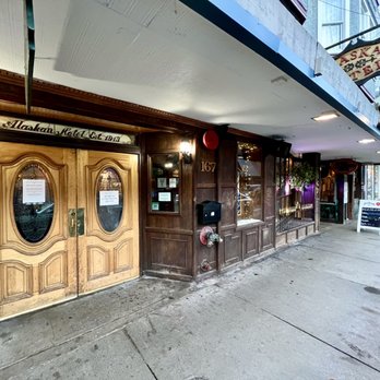 The Alaskan Hotel & Bar - Alaskan Hotel entrance to the left. The bar has its on entrance on the right with a sign set up on the sidewalk. - Hotels Near Me - Juneau, Alaska