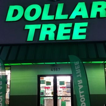 Dollar Tree - The image shows the exterior of a Dollar Tree store at night, featuring a large illuminated green sign with the store's name. The storefront has double glass doors with visible signage and a few flags or banners on either side. The store's address, 4567, is displayed above the entrance. The parking lot in front is partially visible, with some parking lines and a small section of a vehicle. The overall scene is dark except for the bright store signage. - Discount Store Near Me - El Monte, California