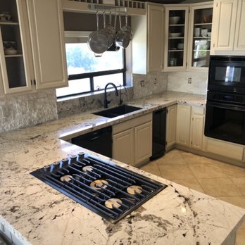 Bay Custom Marble & Granite - a kitchen with white cabinets and black appliances - Countertop Installation Near Me