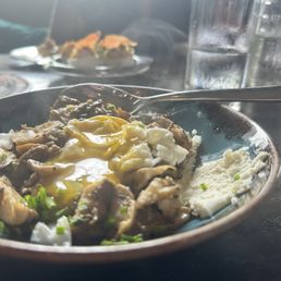 Local mushrooms. Because in a fun-guy! - A dish featuring sautéed mushrooms with a poached egg on top and a side of mashed potatoes, served on a blue plate at a restaurant.