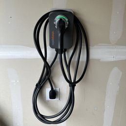 50 amp NEMA 14/50R outlet install - A ChargePoint electric vehicle charging station with a black cable is mounted on a wall in a garage or utility area.