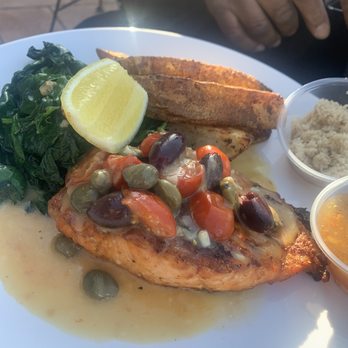 Briggs Corner Pizzeria - Brown Sugar Salmon Fingerling potatoes and spinach - A meal featuring grilled salmon topped with capers and cherry tomatoes, served with lemon, sautéed greens, potato wedges, and side dishes. - Pizza Near Me - Attleboro, Massachusetts