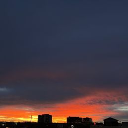 A sunset with vibrant orange and pink hues over Albuquerque, with the Trader Joe's store visible in the lower right corner.