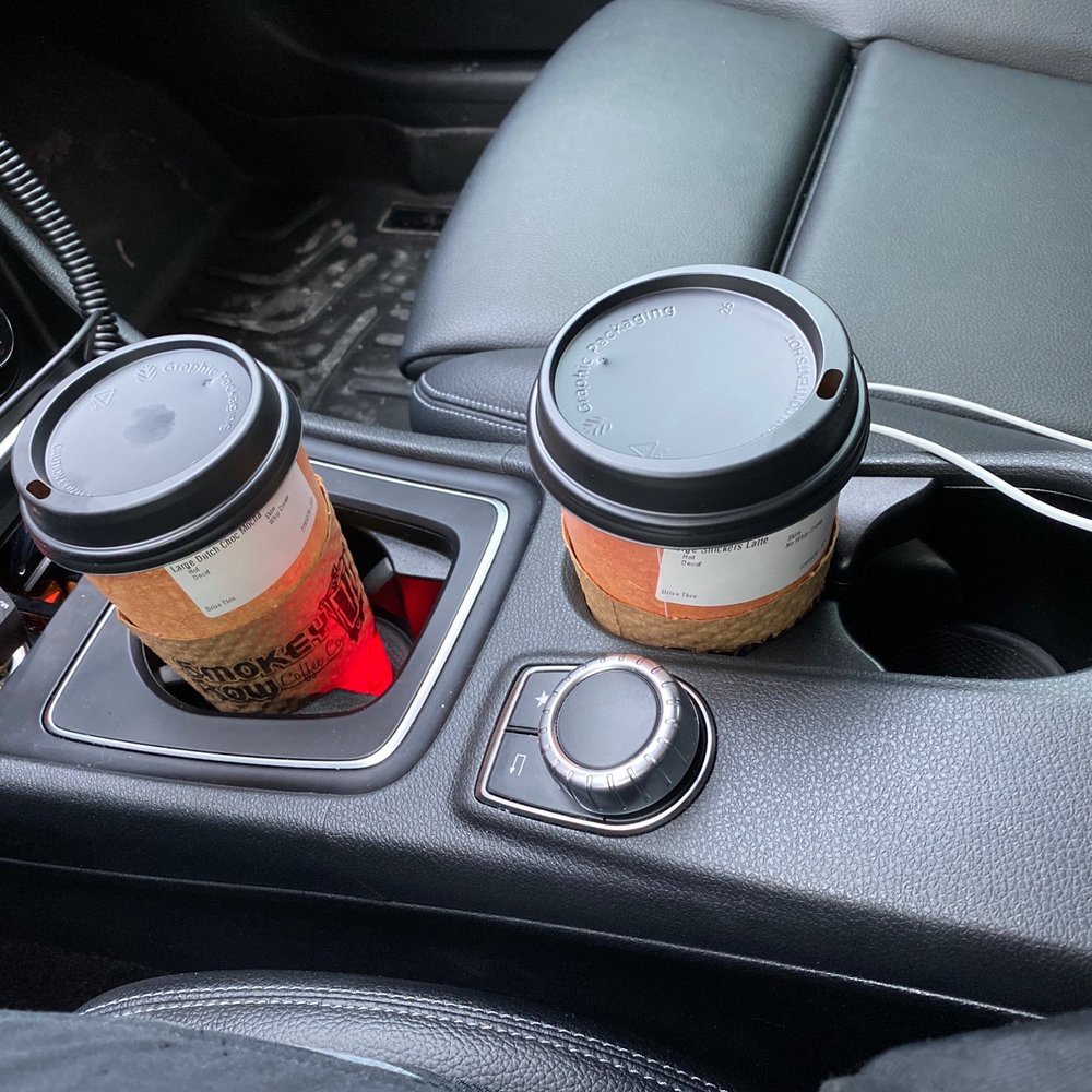two cups of coffee in the center console of a car