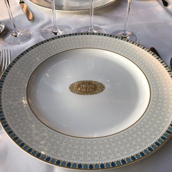 Le Train Bleu - Beautiful table settings feature the restaurant's emblem. - French Near Me - Paris, 75 Le Train Bleu - Beautiful table settings feature the restaurant's emblem. - French Near Me - Paris, 75