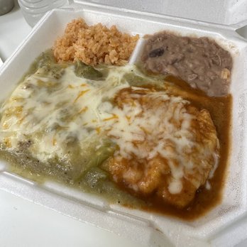 Papa Nachos - The image shows a styrofoam takeout container filled with Mexican food. It contains a portion of rice, refried beans, a cheese-covered enchilada with sauce, and a meat dish with sauce and melted cheese. The container is placed on a white surface, with a water bottle and small containers visible in the background. - Mexican Near Me - Albuquerque, New Mexico