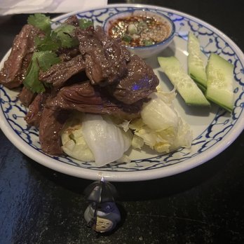 Sabay - BBQ Beef - A dish featuring cooked beef garnished with cilantro, served with cucumber slices, pickled vegetables, and a small bowl of dipping sauce. - Thai Near Me - Elmhurst, New York
