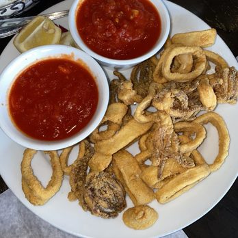 Filetto’s - Fried Calamari with Fra Diavolo Sauce - A plate of fried calamari rings and tentacles served with two bowls of red dipping sauce and lemon wedges. - Italian Near Me - Commack, New York