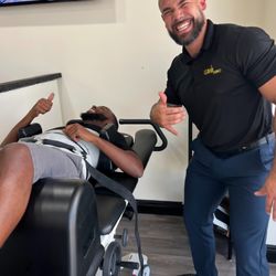 Chiro Studio - Dr. Junior at Chiro Studio in Cocoa, FL and a patient using a decompression table, both giving a thumbs up.