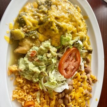 El Comal - Green Chile Chicken Stuffed Sapopilla - A Mexican meal featuring rice, refried beans, guacamole, shredded lettuce, tomato slice, and cheesy potatoes on a white oval plate. - Mexican Near Me - Santa Fe, New Mexico
