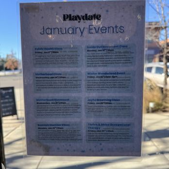 Playdate - A poster is affixed to a glass window, listing January events at Playdate in Westminster, CO. The poster includes event titles, dates, times, and brief descriptions of activities such as fitness classes, movement classes, and wellness sessions. The background shows outdoor scenery with trees and parked cars, and the poster is partially reflective, with some glare and shadows visible. - Indoor Playcenter Near Me - Westminster, Colorado