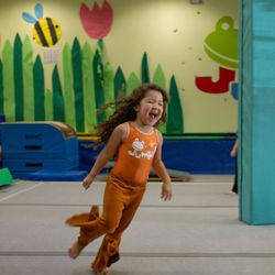 Jump! Gymnastics - A gymnast runs around the gym, smiling and laughing.