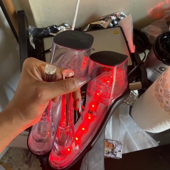 Born Exotic - A person holds two clear plastic cups with black lids above a portable charger with red LED indicator lights, on a black surface. - Lingerie Near Me - Newark, New Jersey