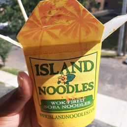 a hand holding a container of noodles a hand holding a container of noodles