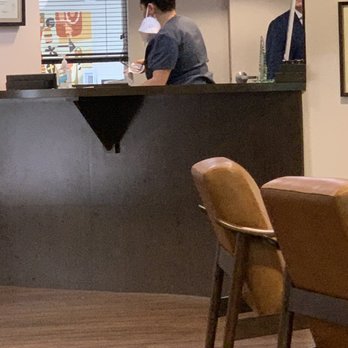 Brian D Haas, MD - Receptionist not wearing her mask.  Mask actually hanging from her left ear. Also notice chairs are close together. - Ophthalmologists Near Me - Orlando, Florida