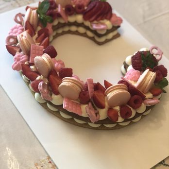 Macarons by Mila Pastry - Letter C cake with macarons, strawberries, raspberries, and pink candy. - Custom Cakes Near Me Macarons by Mila Pastry - Letter C cake with macarons, strawberries, raspberries, and pink candy. - Custom Cakes Near Me