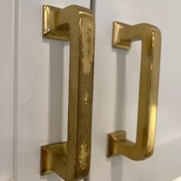 Mission Drawer Pull Aged Brass. Inconsistent quality - The image features two brass drawer pulls attached to a white cabinet. The left handle shows visible signs of aging, including tarnish and peeling finish, while the right handle appears newer and in better condition. The handles are mounted vertically and are used for opening drawers or cabinet doors.