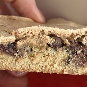 Zooies - a hand holding a piece of chocolate chip cookie - Bakeries Near Me - Los Angeles, California