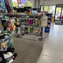 New products - A retail store interior featuring sock displays on the left, a central rack with toys and accessories, and a glass entrance door with parking lot outside.