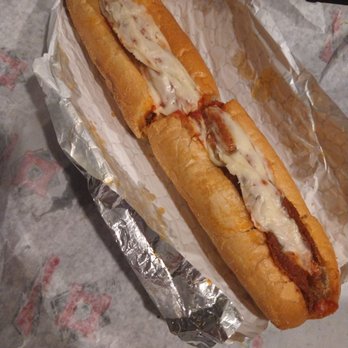 Central Pizza - eggplant parmesan sub  the best sub for my pregnancy craving at 36 weeks - A hot dog with a sausage inside a bun, topped with melted cheese and ketchup, is presented on a piece of crumpled aluminum foil. The hot dog appears to be freshly prepared, with the cheese slightly melted and the bun toasted. It is placed on a paper-lined surface, possibly in a casual dining or takeout setting. - Pizza Near Me - Franklin, Massachusetts