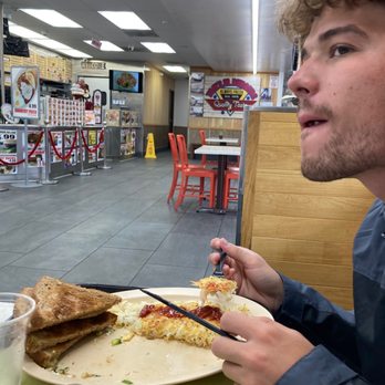 Tom's Jr Burgers - a man eating a slice of pizza - New American Near Me - Downey, California Tom's Jr Burgers - a man eating a slice of pizza - New American Near Me - Downey, California