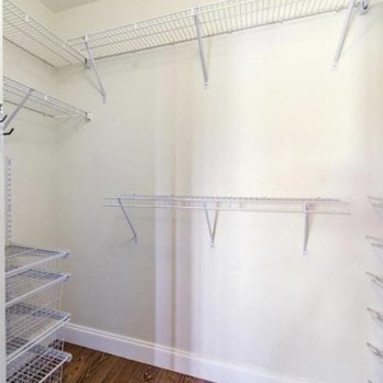 RA Express Services - A walk-in closet features white wire shelves mounted on the walls, with a hardwood floor and a plain white wall. - Painters Near Me