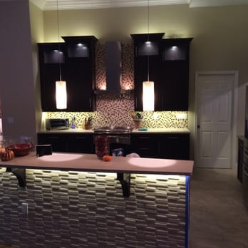 KGT Builders - a kitchen with black cabinets and white countertops - General Contractors Near Me - Naples, Florida