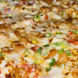 Seafood Pizza - A close-up image of a seafood pizza featuring a baked crust topped with melted cheese, small pieces of seafood such as shrimp or scallops, and chopped green onions. The pizza appears freshly baked with a golden-brown crust and a variety of toppings evenly distributed across the surface.