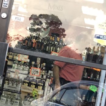 UP Liquor - the reflection of a man in a store window - Beer, Wine & Spirits Near Me - Houston, Texas