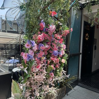 LH Rooftop - A large flower arrangement with pink, purple, and white flowers is placed outside a building entrance, with greenery and a butterfly decoration. - Cocktail Bars Near Me - Chicago, Illinois