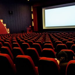 a large screen and rows of red seats