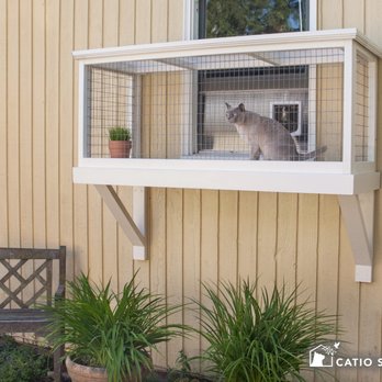 Catio Spaces - A small window box provides the kitty a birds eye view of the garden, and the wood is painted white to complement the home. - Pet Services Near Me