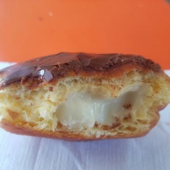 Jax Donuts - Inside the Boston Creme donut.  Didn't get any custard til half way through. - A donut with chocolate glaze on top, partially eaten to reveal a creamy custard filling inside. - Donuts Near Me - Orange, California