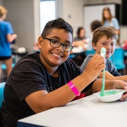 Apex Centre - Summer camp participant smiling with his craft activity.