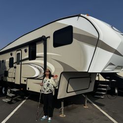 Independent RV - A Cougar 5th wheel with a person standing in front smiling.