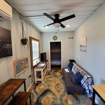 Container City - a living room with a couch, desk, and fan - Resorts Near Me - Burnet, Texas