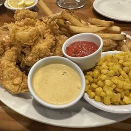 Fried chicken and shrimp with a side of fries and corn Fried chicken and shrimp with a side of fries and corn