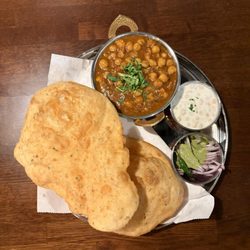 Saffron Indian Cuisine - Chole Bhature - Soft and puffy fried leavened bread served with spiced tangy gravy of chick-peas; comes with onions and pickles on the side.