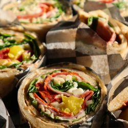 Herb & Fire - Grandville - A top-down view of pinwheel-style wraps. Each slice reveals colorful concentric circles of ham, pepperoni, greens, and yellow...