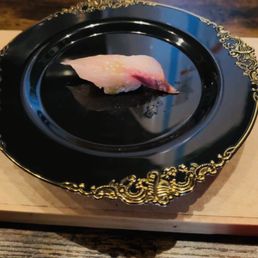 a piece of sushi on a black plate