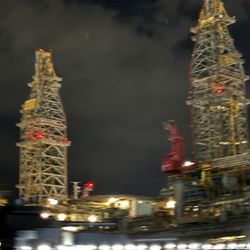 Galveston Haunted Harbor Tours - Massive towers rise against the night sky, their red lights glowing like watchful eyes above the harbor...