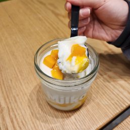 a hand holding a spoon over a bowl of yogurt a hand holding a spoon over a bowl of yogurt