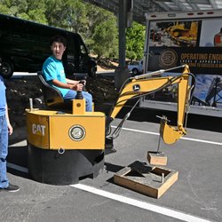 Sabrina Martin of Operating Engineers Apprenticeship lets eighth-grader Edgar Baca Salas try a backhoe during a career day event.