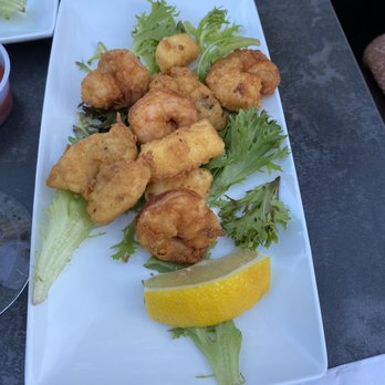 Patio 03907 - Appetizer pick 2 shrimp and haddock - Fried seafood pieces are arranged on a white rectangular plate with lettuce leaves and a lemon wedge, served outdoors. - Seafood Near Me - Ogunquit, Maine