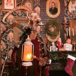 Prometheus Esoterica - Books, old pictures, dolls and a sort of goat head mounted on a robed figure carrying a lamp perhaps to represent Krampus